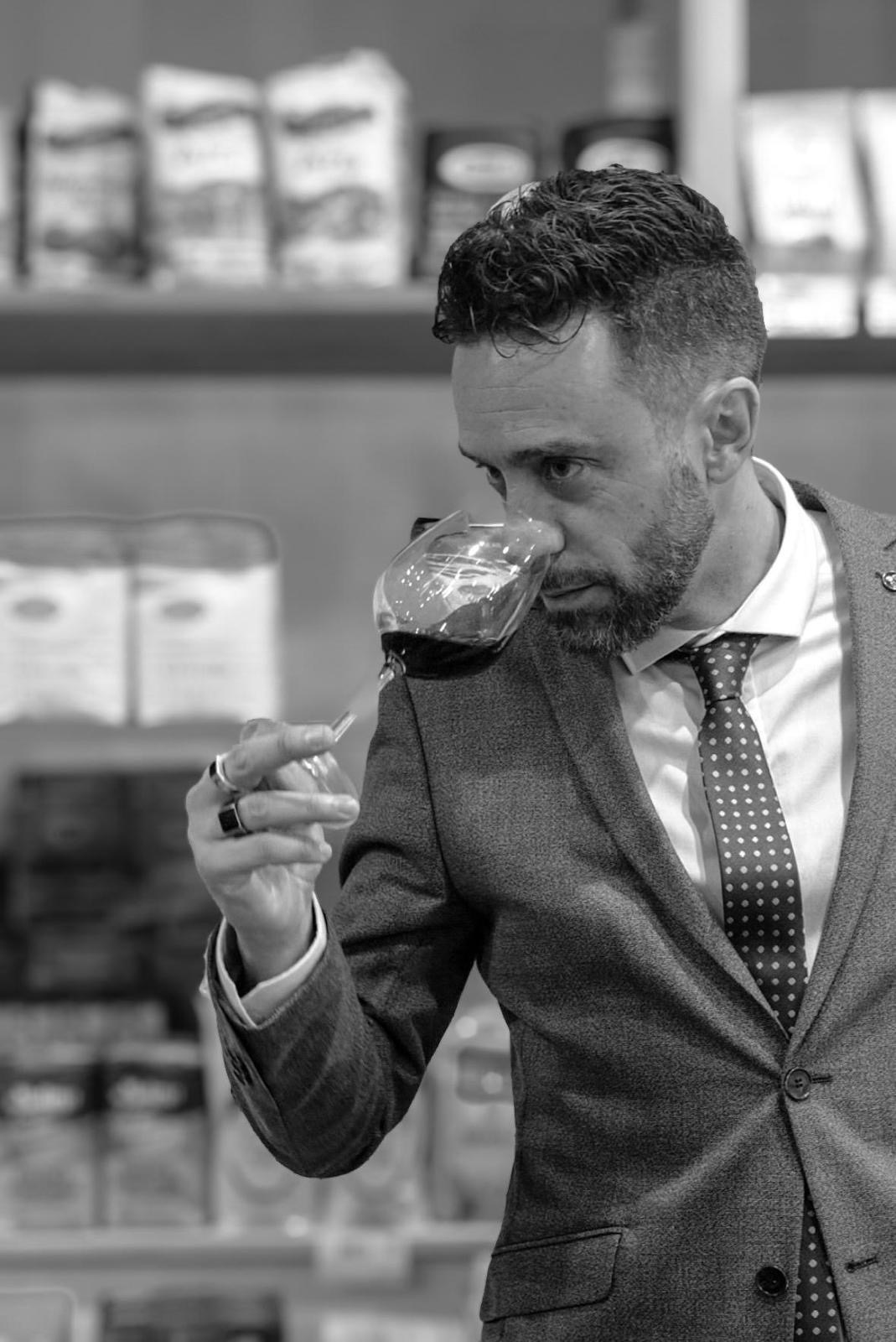 Andrea Rocca in bianco e nero mentre esamina i profumi di un calice di vino.