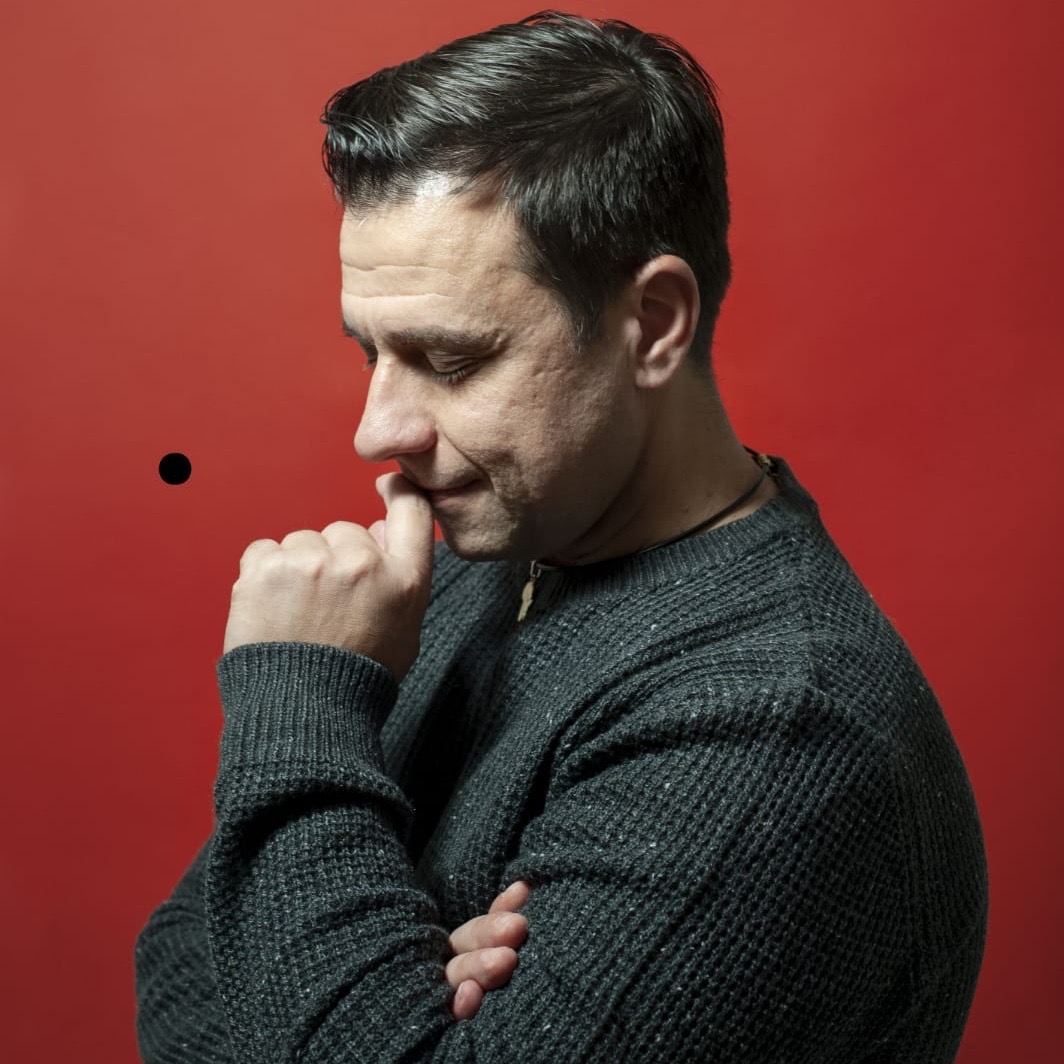 Ritratto di Fabrizio Macchiagodena su fondo rosso.